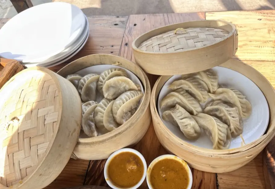 木桌上两屉竹蒸笼里的蒸饺,旁边配两碟蘸料